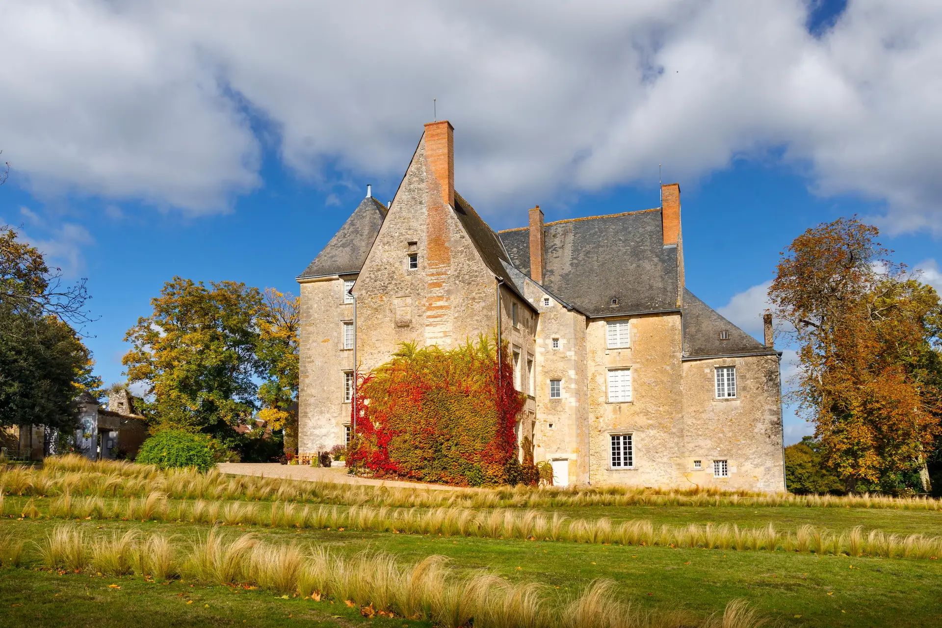 Château en pierre aux tours pointues, entouré d’arbres d’automne