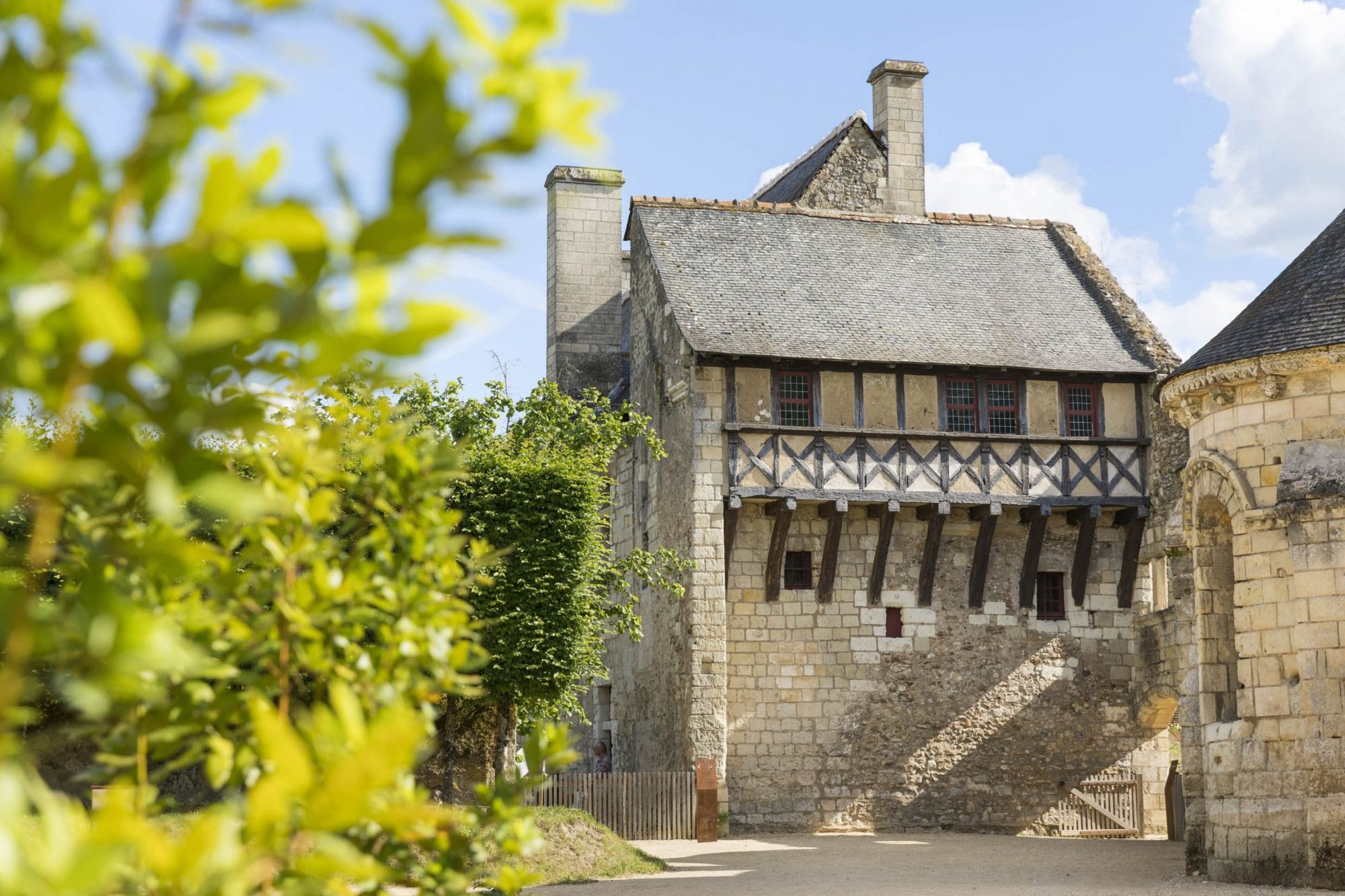 Façade en pierre d’une maison d’écrivain, avec une galerie en bois, vue à travers la végétation